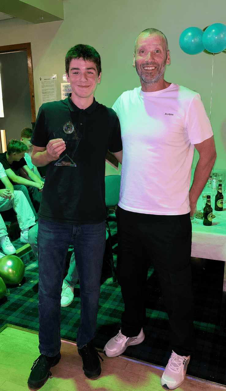 A young award recipient standing with a Spartinios coach